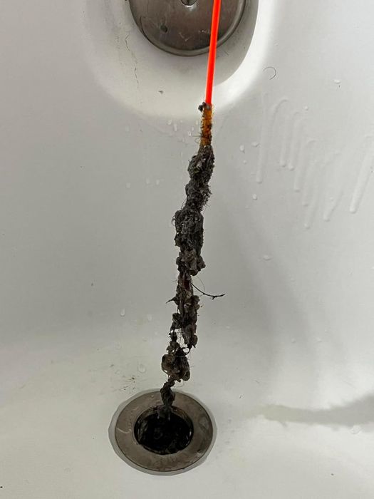 A drain snake pulls out hair and debris from a bathtub drain.