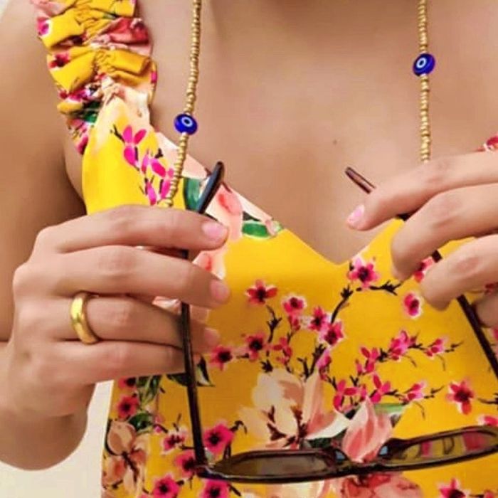 a model wearing a beaded chain connected to a pair of sunglasses