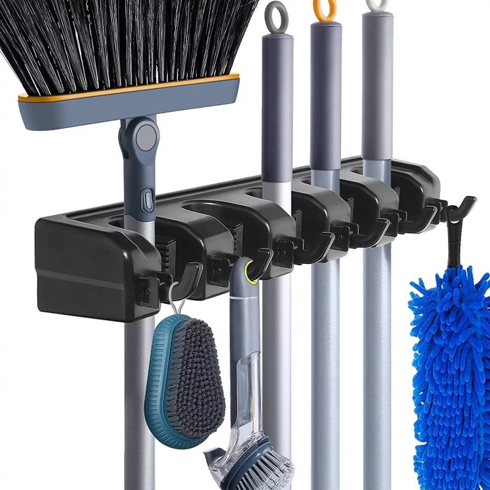 A wall-mounted broom holder organizing a broom, mop, and other cleaning tools, perfect for home storage and keeping everything in order