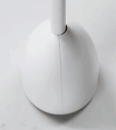 A gif showing a hand lifting the white and blue rounded toilet brush out of its canister, revealing how the canister automatically opens.