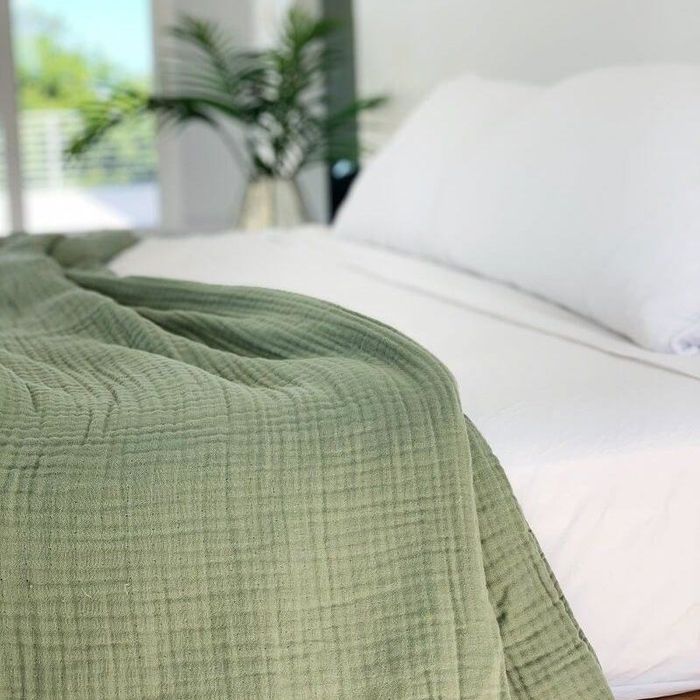 a detailed shot of the green blanket laid out on a bed