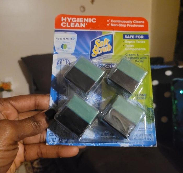 A hand holding a package of Soft Scrub Hygienic Clean toilet cleaning blocks (4-pack), advertised as safe for toilet tanks and providing continuous cleaning for up to 16 weeks.