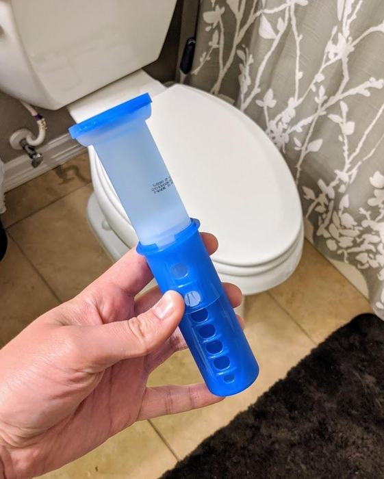 A reviewer demonstrates the Scrubbing Bubbles toilet gel stamp in their hand.