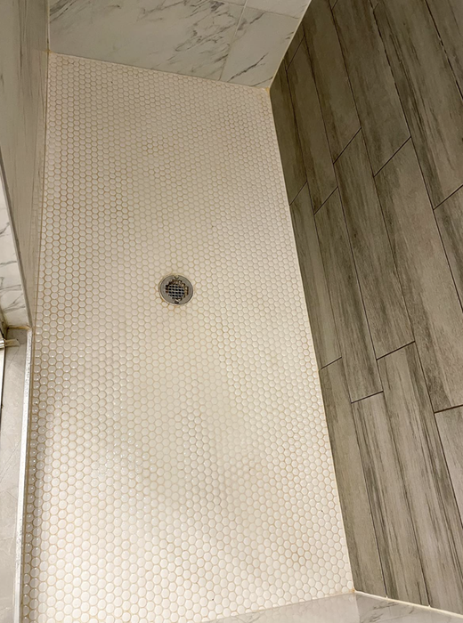 The same reviewer's after photo showing their shower tiles now perfectly clean