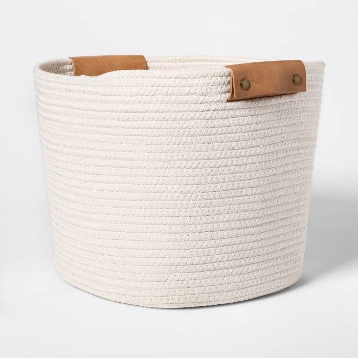 A white woven basket featuring leather handles