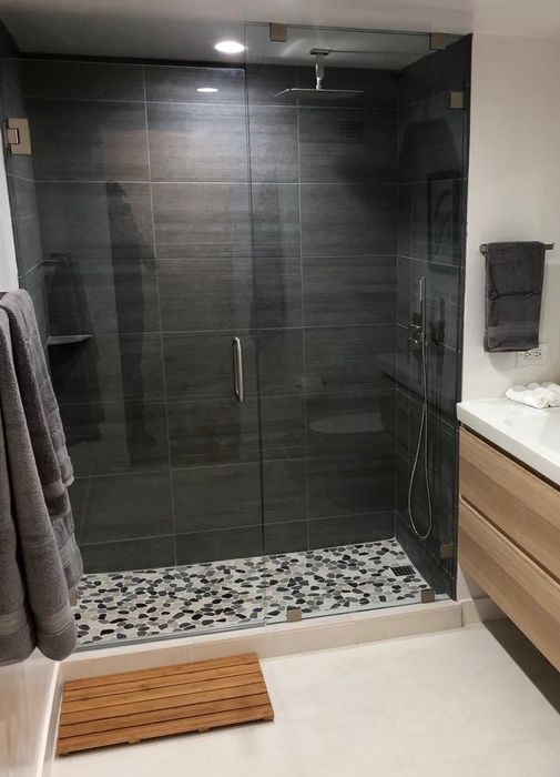 Reviewer photo showing the bamboo bath mat placed in front of a walk-in shower.