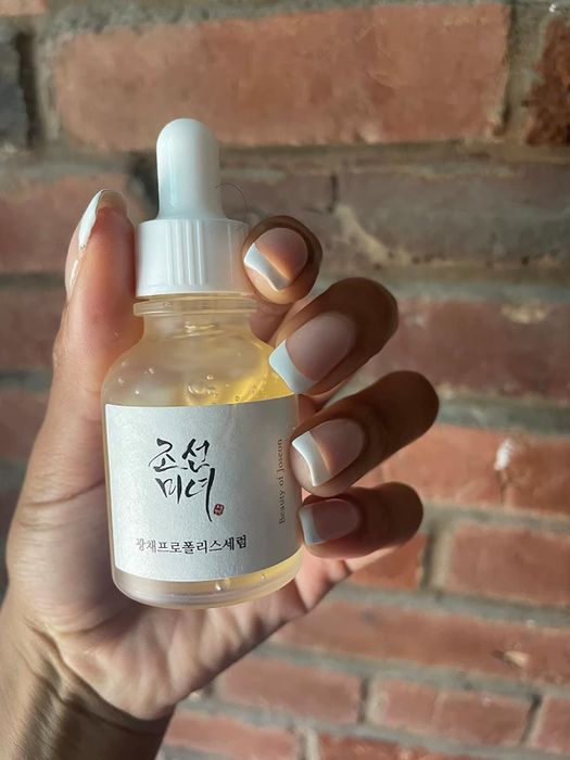 A reviewer's hand holding up the oil bottle.