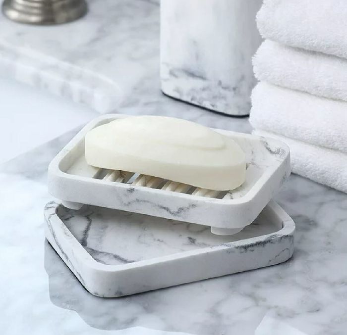 Two elegant white marble soap dishes holding a bar of soap