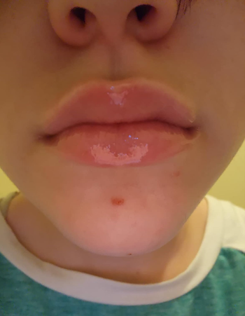 A reviewer showcasing glossy, hydrated lips.