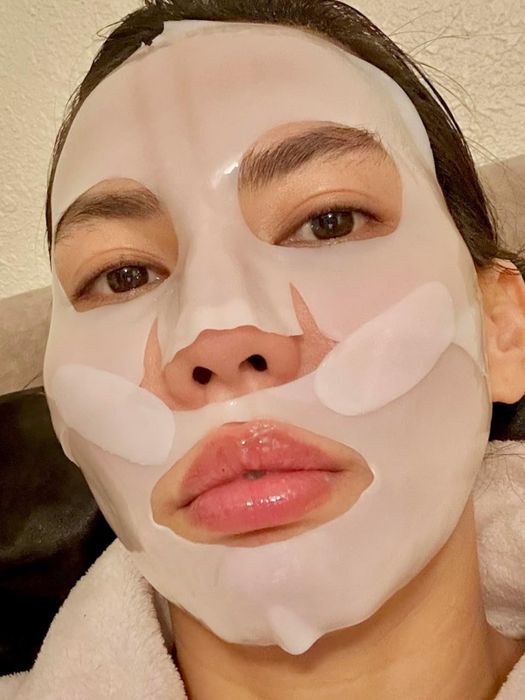 A person wearing a white sheet mask covering their entire face.