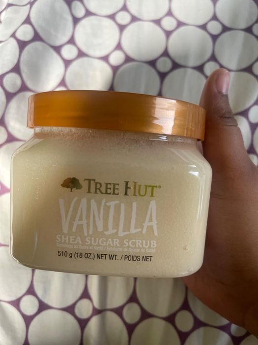 A person holding a jar of Tree Hut Vanilla Shea Sugar Scrub, 510g (18oz)