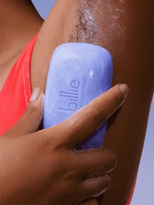 A person using the Billie body buffer to exfoliate their underarm in a personal care environment.