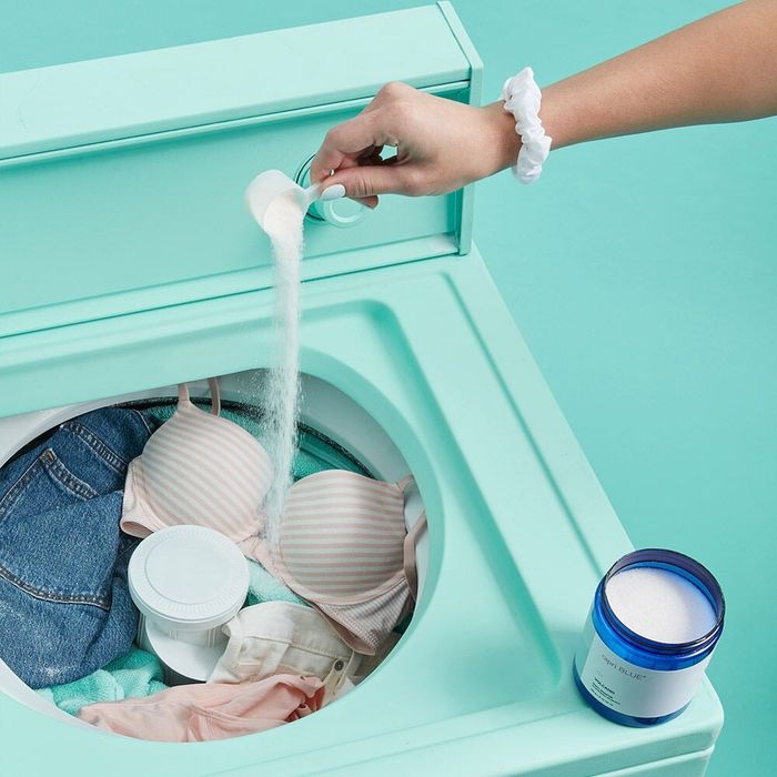Model pouring a little bit of the scent booster into their laundry