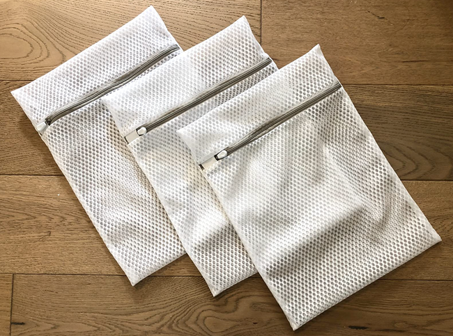 A set of three white zippered mesh bags with a honeycomb pattern