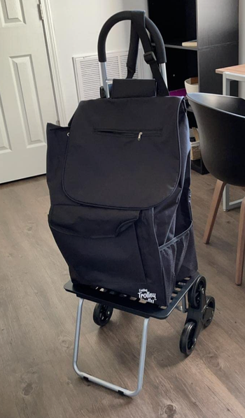 The trolley equipped with a black backpack attached to it.