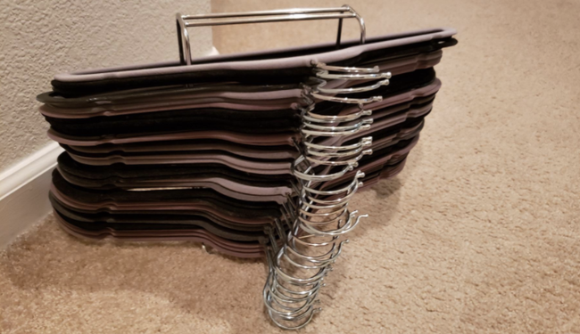 Clothes hangers almost overflowing on a metal rack.