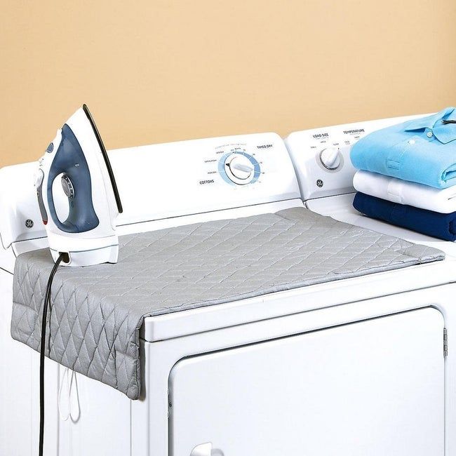 The ironing pad resting on a washing machine.