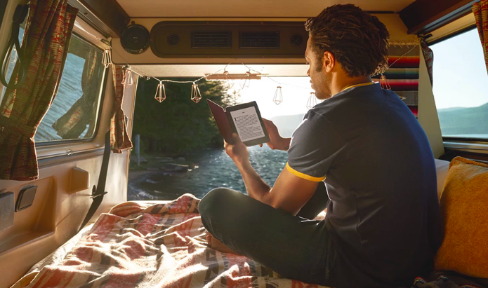 A person enjoys reading a Kindle while on a car camping trip.
