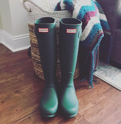 Green knee-high Hunter rain boots placed inside the house