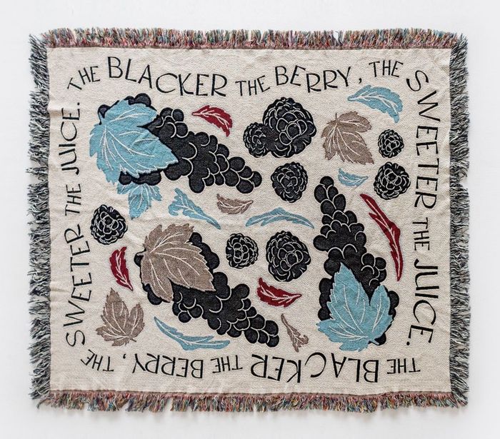 A blanket adorned with blackberries and leaves, bordered with the phrase 'the blacker the berry, the sweeter the juice'.