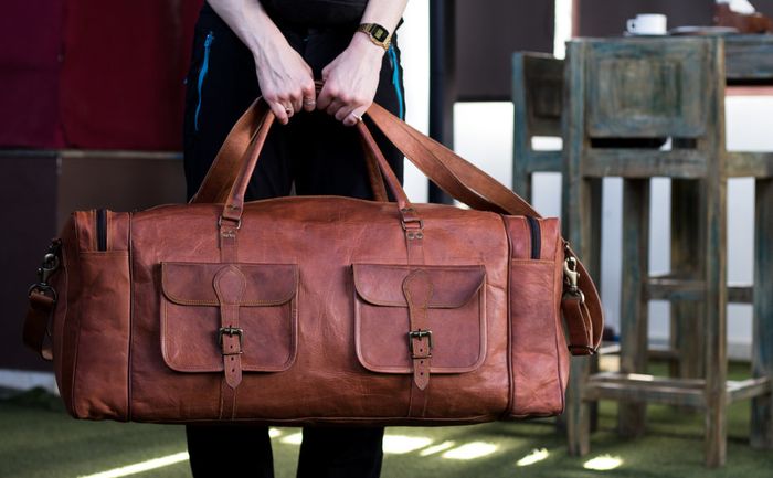 A large rectangular carry-on bag, complete with a clip-on shoulder strap, multiple pockets, and buckles to keep everything secure.