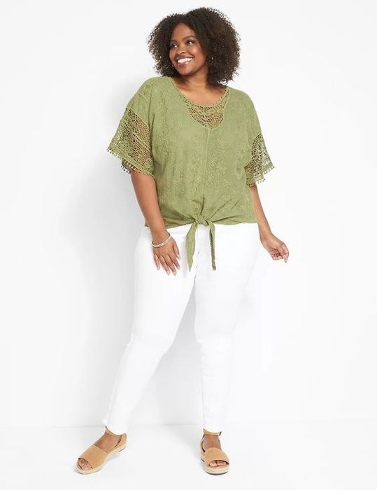 The model is wearing a green short-sleeve top paired with white pants.