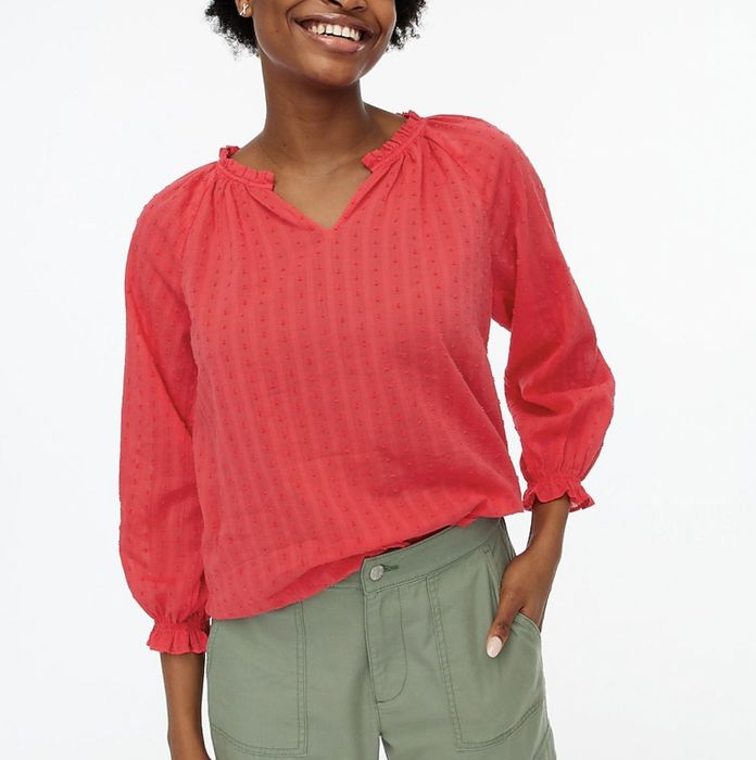 The model is wearing a peach top, slightly tucked into green pants.