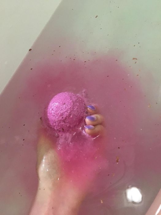 hand places bath bomb into the water
