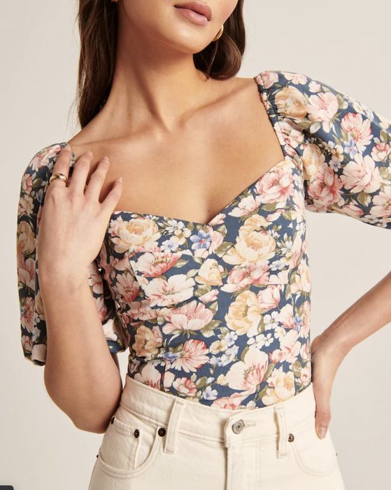 The floral corset top tucked neatly into white jeans