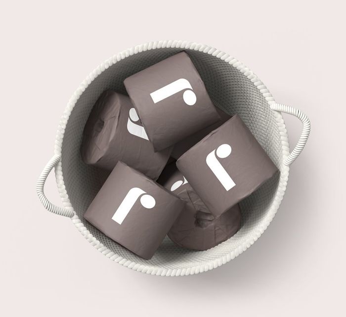 A basket filled with toilet paper, each roll wrapped in gray paper adorned with a white 'R'.