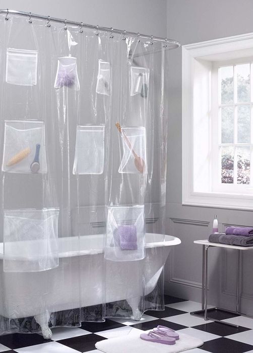 transparent shower curtain with mesh pockets holding a towel, shampoo, brush, and other items