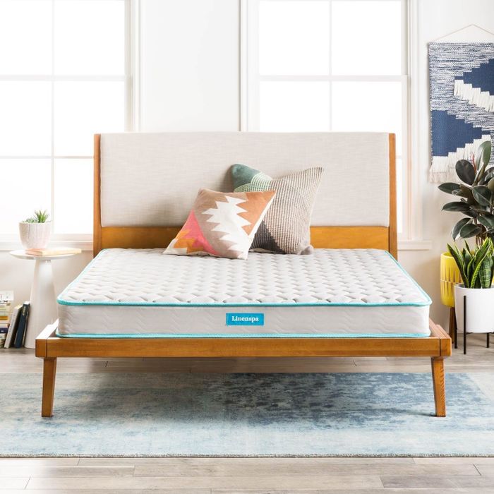 A mattress placed on a wooden bed frame, complemented with decorative pillows for a cozy and inviting bedroom atmosphere.