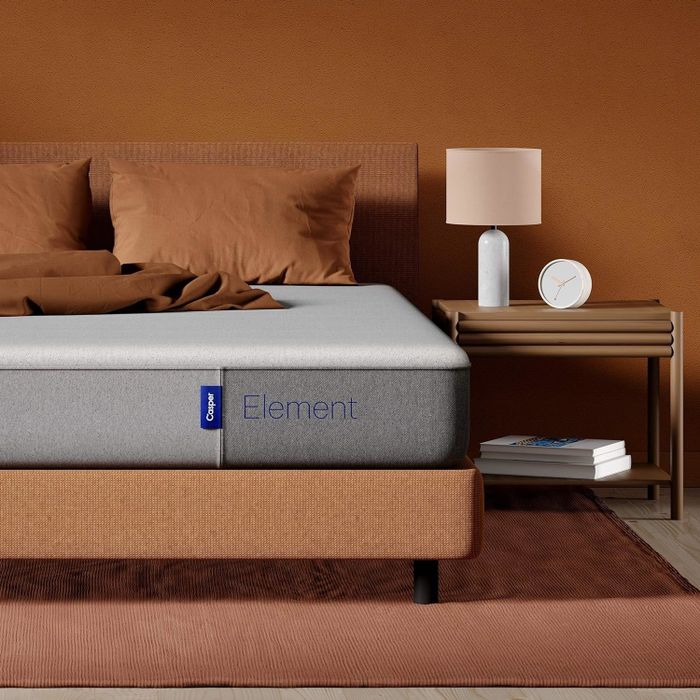 A modern bedroom showcasing a minimalist bed design, complemented by a nightstand with a lamp and clock for a sleek and functional aesthetic.