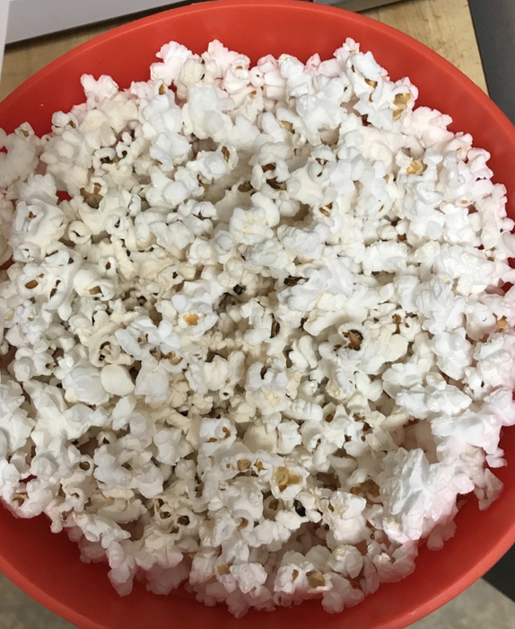 A reviewer showing a bowl of freshly popped popcorn.