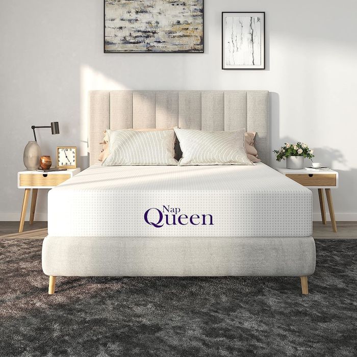 A modern, neatly arranged bed with 'Nap Queen' text on the cozy-looking mattress in a stylish bedroom setting.