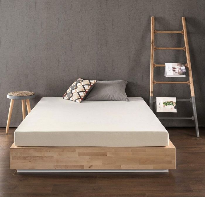 A cream-colored mattress placed on a wooden bed platform, adding elegance and comfort to any bedroom.