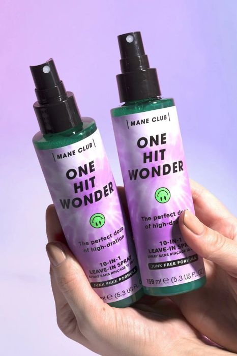 Hands holding two bottles of leave-in conditioner spray.