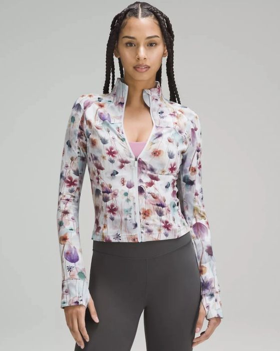 Model wearing the floral jacket zipped up over a pink sports bra.