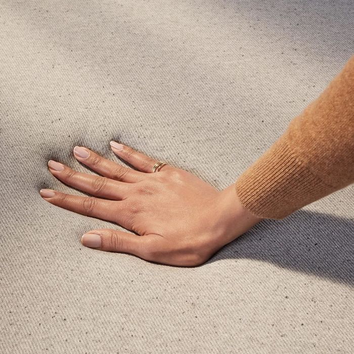A close-up view of a hand pressing down on a mattress, demonstrating its responsiveness and comfort.
