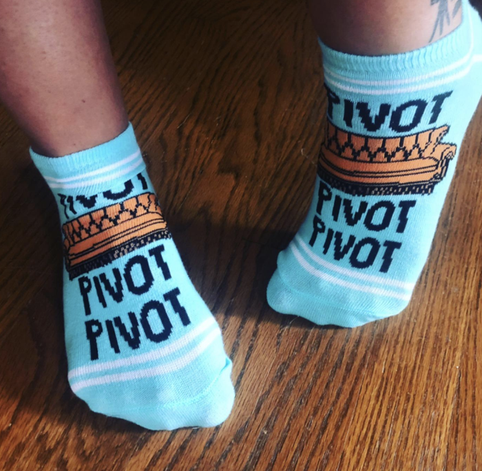 A reviewer sporting a pair of blue socks with a couch pattern design.