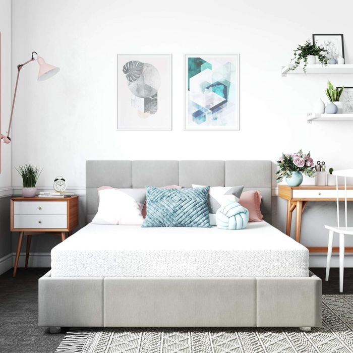 A contemporary bedroom design featuring an upholstered bed, geometric artwork, wood side tables, and decorative touches such as plants and cushions, creating a cozy and modern space.