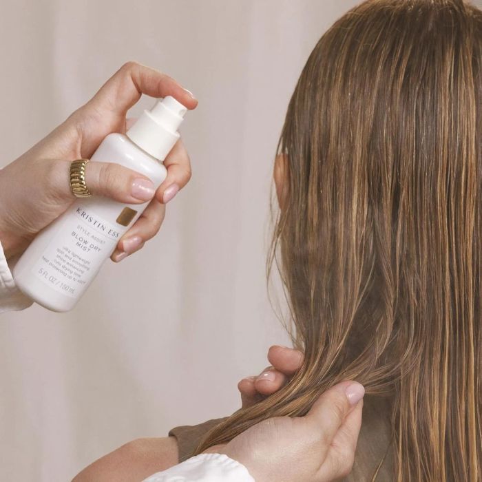 A person applying hair product from a white bottle to another person’s hair, focusing on texture and care.