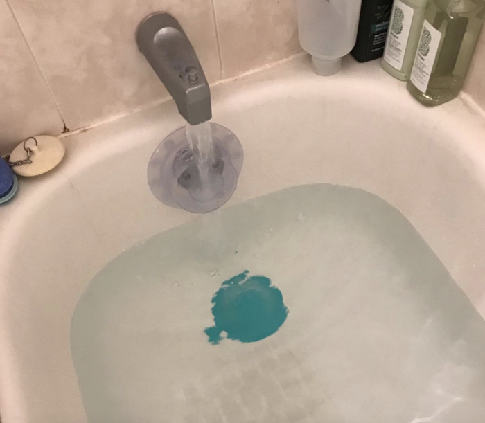 A reviewer photo showing the blue tub stopper in a fully submerged bath.