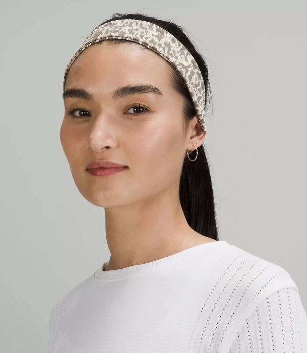 Model wearing the camo headband, with her hair pulled back in a sleek ponytail.