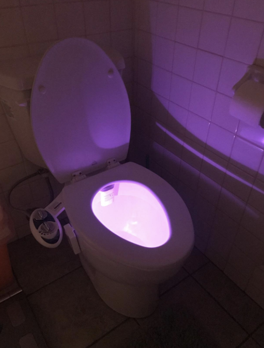 A toilet illuminated with a soft pink glow.