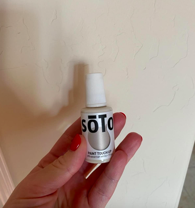 A customer review photo showing them holding the paint next to the wall they just touched up.