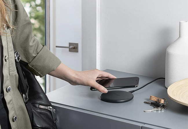 A person placing their phone on a sleek black wireless charging pad