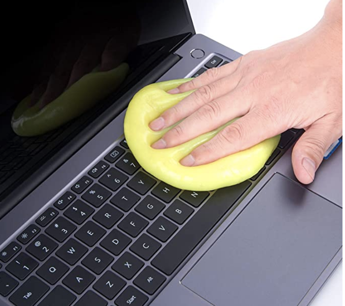 Person cleaning a laptop keyboard with yellow gel