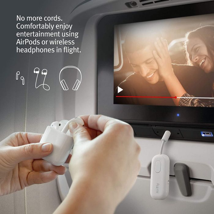 A model aboard a plane, using AirPods to connect to the AirFly transmitter.