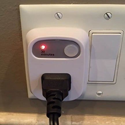 An image showing a black cord plugged into the time outlet, with a small red light lit up next to the words